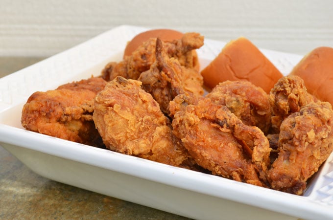 crispy buttermilk fried chicken with a side of dinner roll on a serving dish