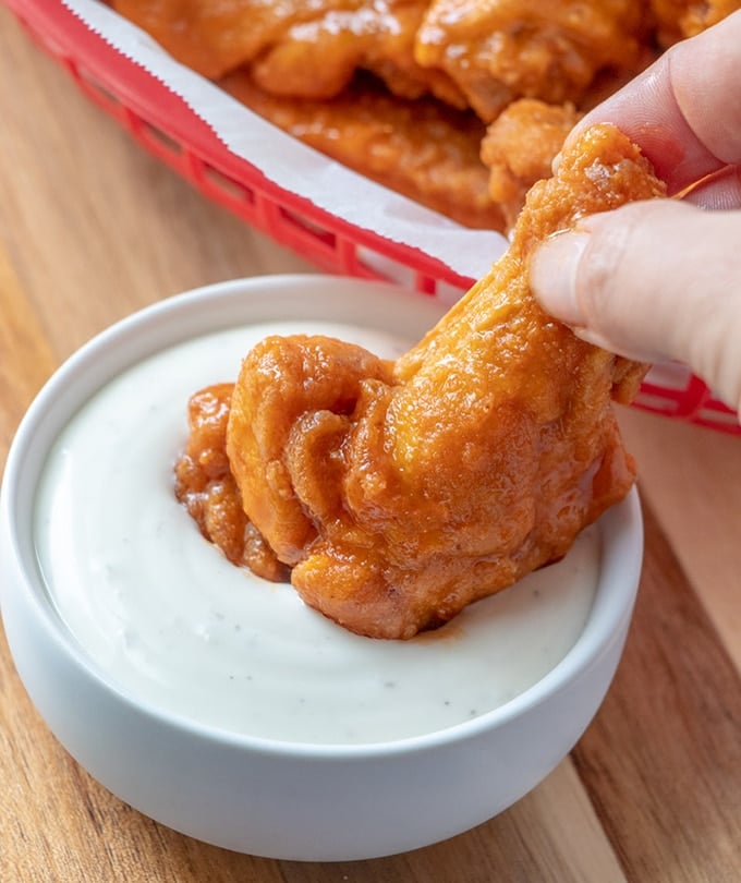 dipping homemade buffalo wings in ranch dressing