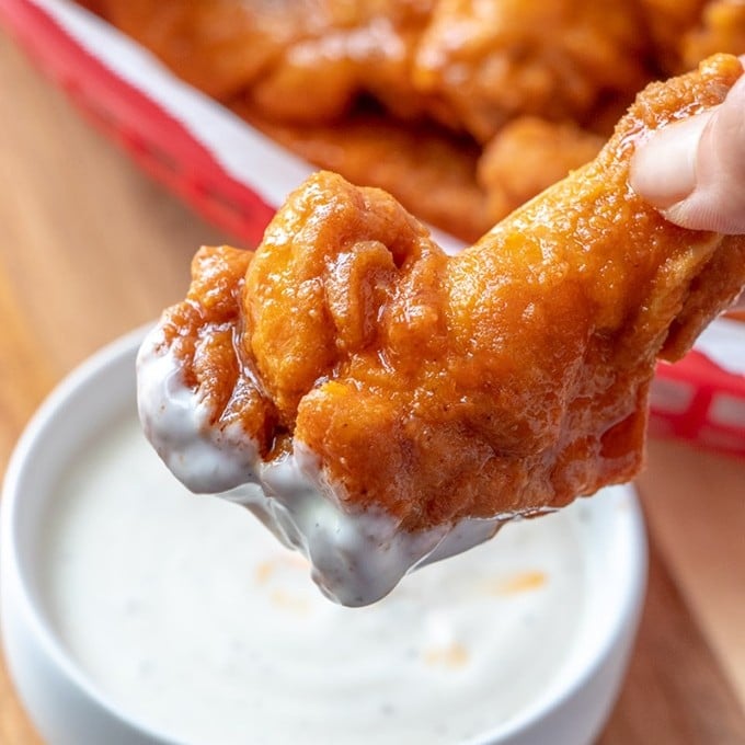 buffalo chicken wings dipped in a bowl of ranch dressing