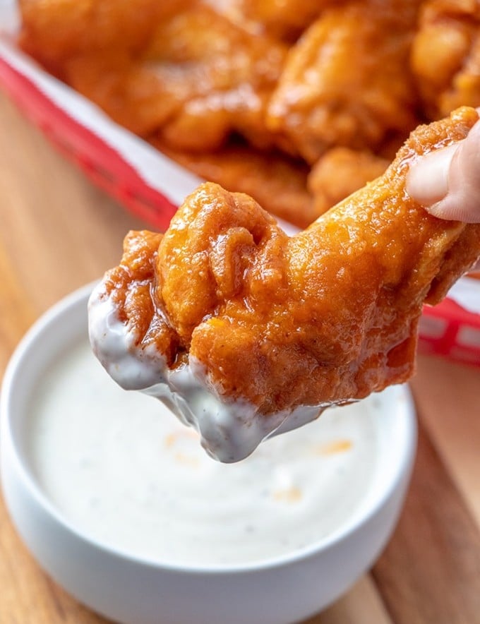 buffalo chicken wings dipped in a bowl of ranch dressing