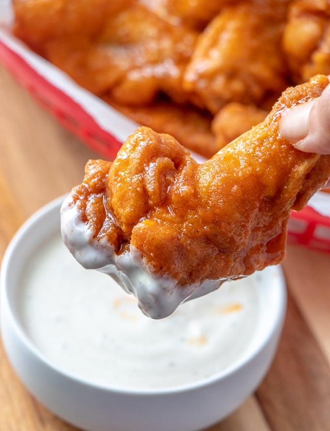 buffalo chicken wings dipped in a bowl of ranch dressing