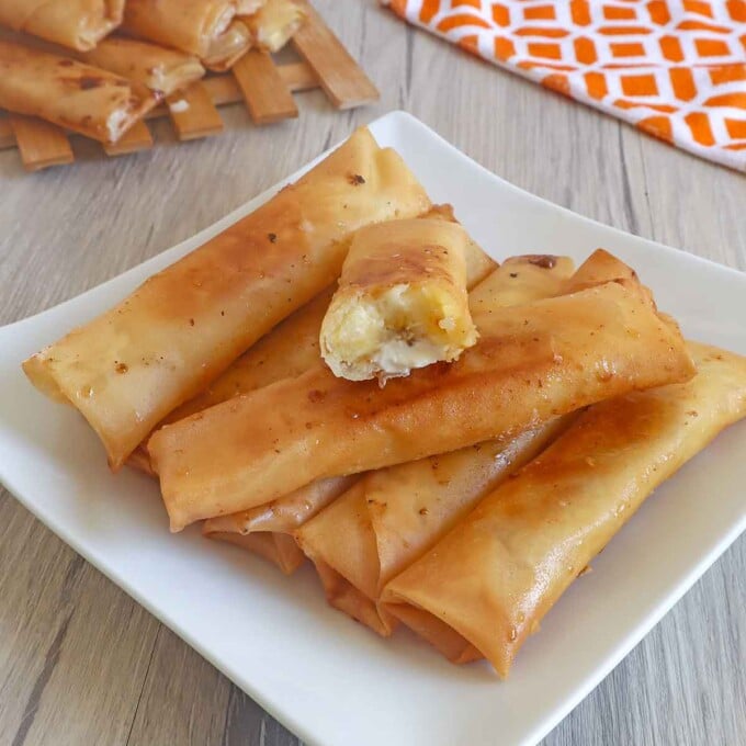 banana cream cheese turon on a white serving platter with a kitchen towel in the background.