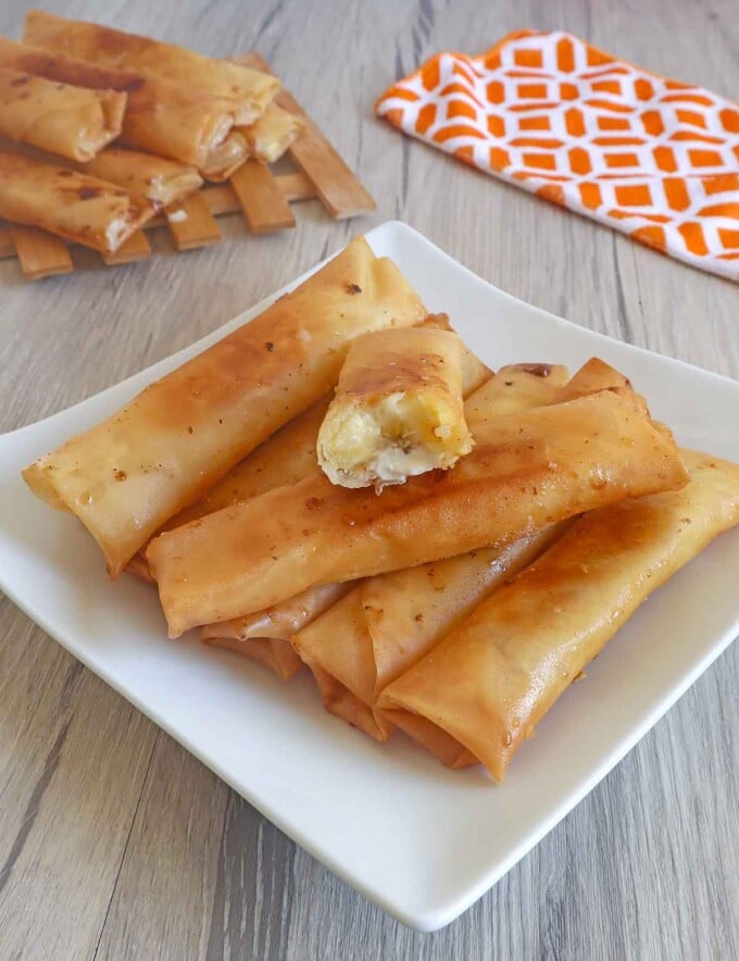 banana cream cheese turon on a white serving platter with a kitchen towel in the background.