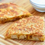 sliced chicken quesadilla with caramelized onions on a cutting board