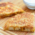 sliced chicken quesadilla with caramelized onions on a cutting board