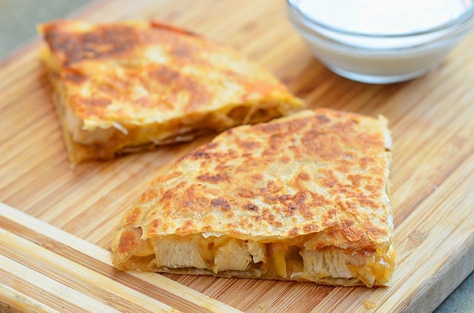 sliced chicken quesadilla with caramelized onions on a cutting board