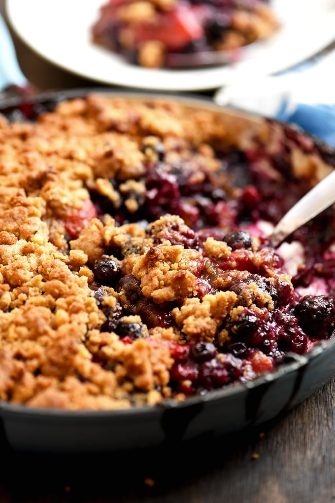 Mixed Berry Crumble in a blue skillet with spoon to serve