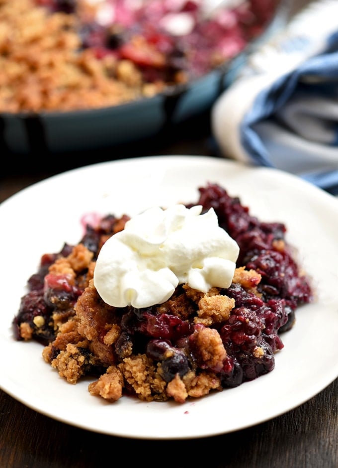 Berry crumble on a white plate with whipped topping
