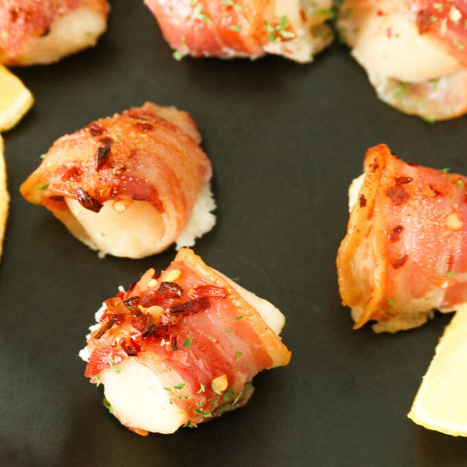 Pancetta-wrapped Scallops on a baking serving platter with as slice of lemon