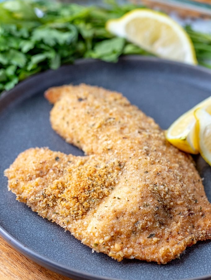 Parmesan Crusted Tilapia on a serving plate with lemon wedges