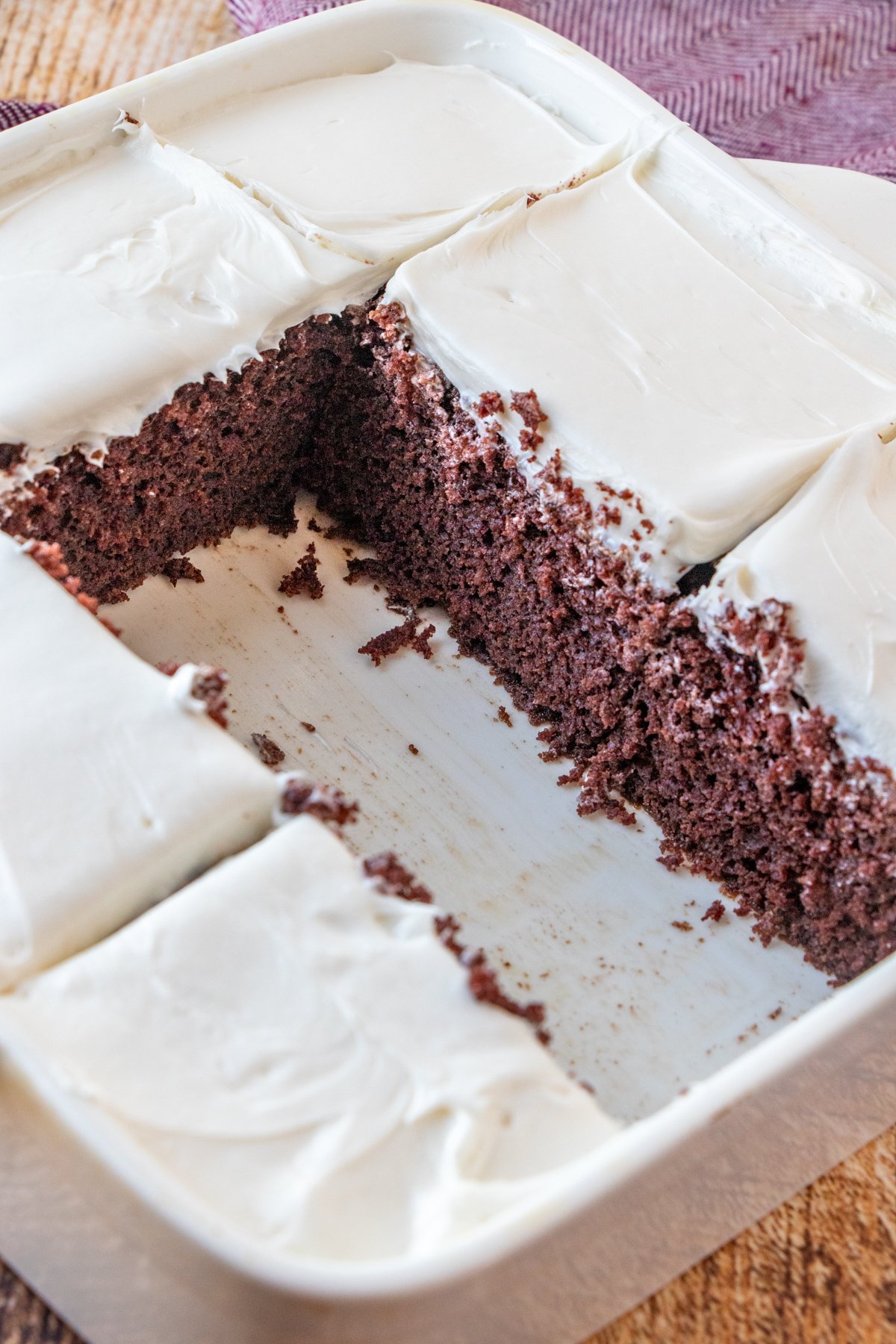 sliced chocolate depression cake with white frosting in a white baking dish