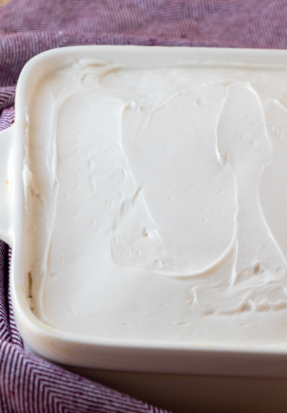cake with white frosting in a white baking dish