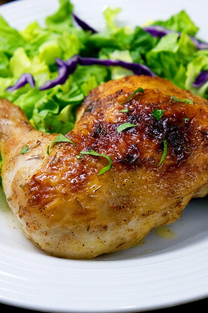 roasted chicken served on a white plate with green salad