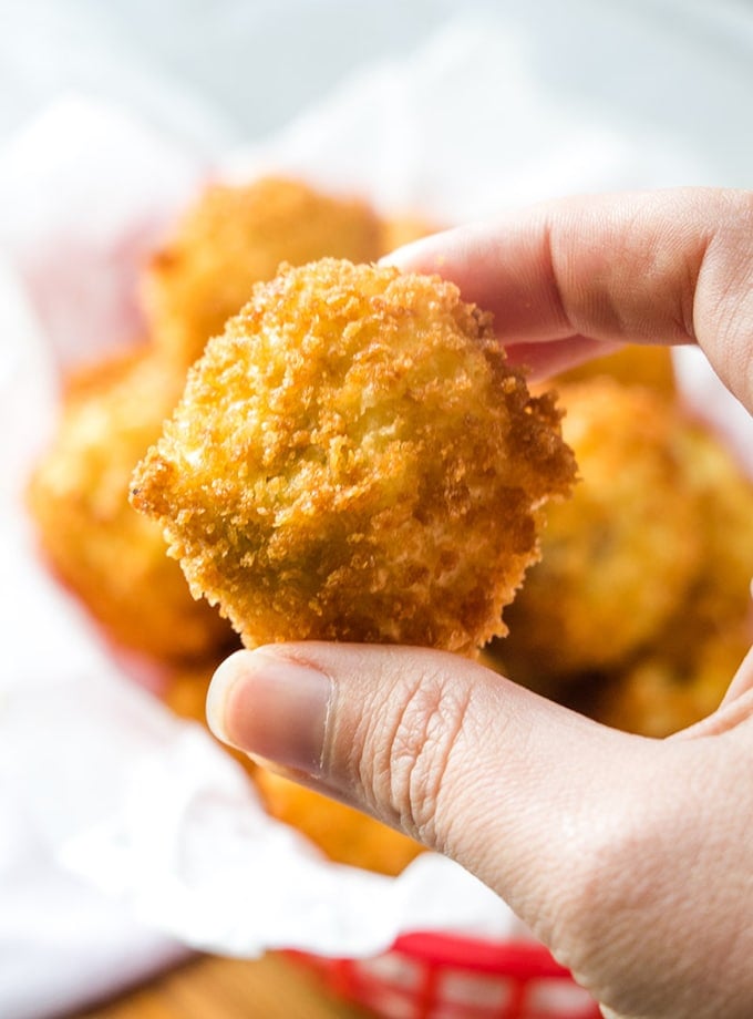 holding mashed potato croquettes with fingers
