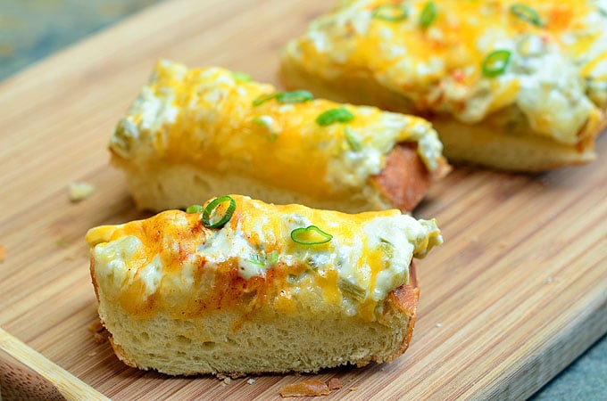 Howell's Bread with mayo, diced green chiles, and cheese on crusty French bread is quick and easy to make and perfect for feeding a crowd. With loads of cheesy goodness and a kick of spice, this cheesy bread is seriously addicting!