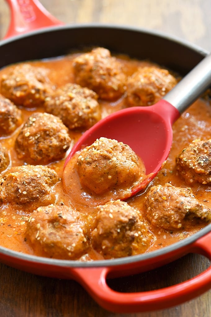 serving beef meatballs in tomato gravy with a spoon