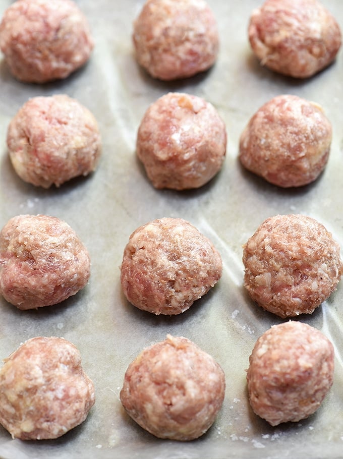 raw beef meatballs on a parchment-lined baking sheet