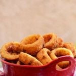 crispy onion rings in a ceramic container with a side of dipping sauce