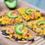 Southwestern Tortilla Pizza topped with black beans, corn, tomatoes, avocados, and creamy enchilada sauce. It's light, crispy, and packed with flavor!