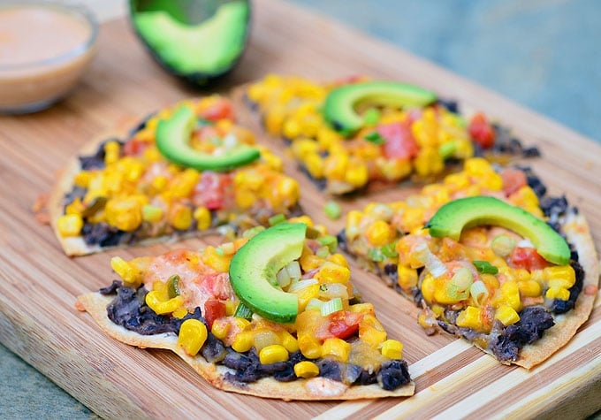 Southwestern Tortilla Pizza topped with black beans, corn, tomatoes, avocados, and creamy enchilada sauce. It's light, crispy, and packed with flavor!