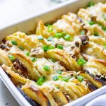 Hasselback Potatoes with Parmesan and Roasted Garlic in a white casserole dish