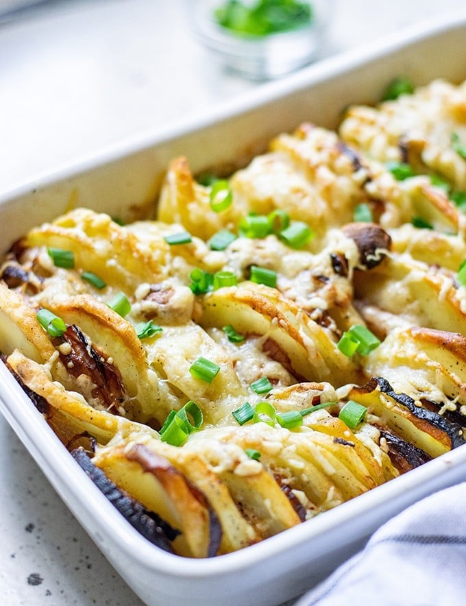 Hasselback Potatoes with Parmesan and Roasted Garlic in a white casserole dish