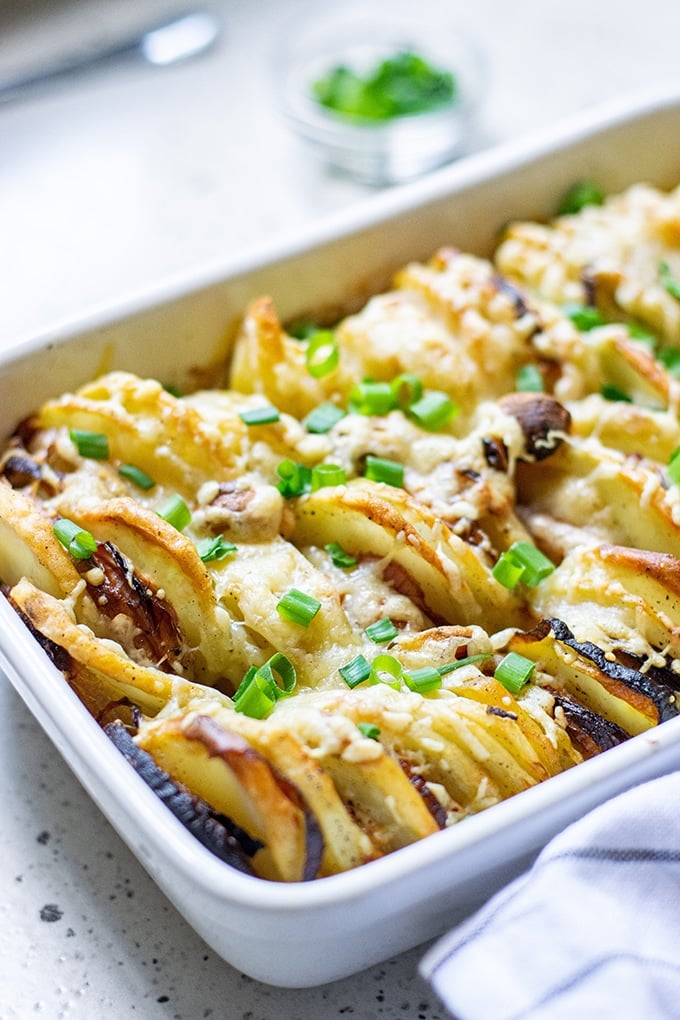 Hasselback Potatoes with Parmesan and Roasted Garlic in a white casserole dish