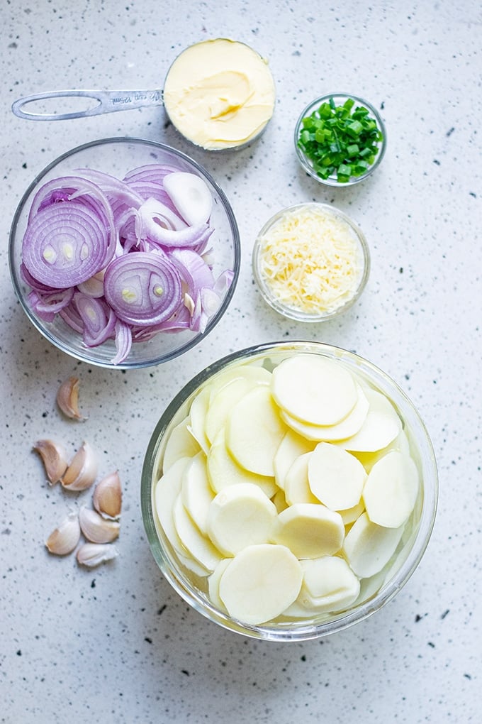 sliced potatoes, sliced red onions, butter, garlic, parmesan cheese, and green onions