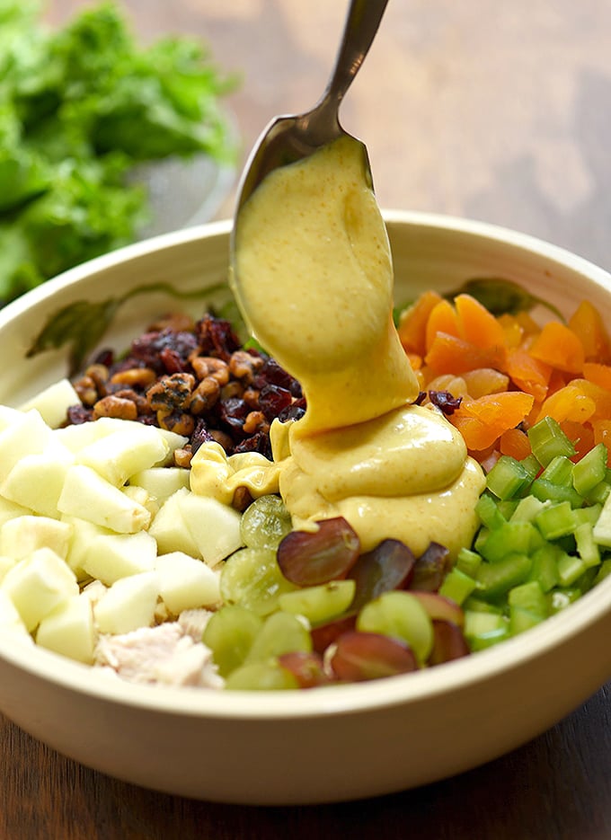 drizzling curry mayo dressing on chicken salad with apples, grapes, dried, fruit, celery, and walnuts