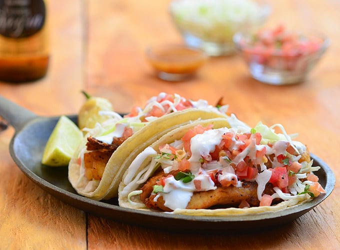 Blackened tilapia fish tacos seasoned with an amazing spice rub and topped with shredded cabbage, fresh </em>pico<em> de gallo, and crema Mexicana. They're a fresh, healthy, and easy meal for busy weeknights!