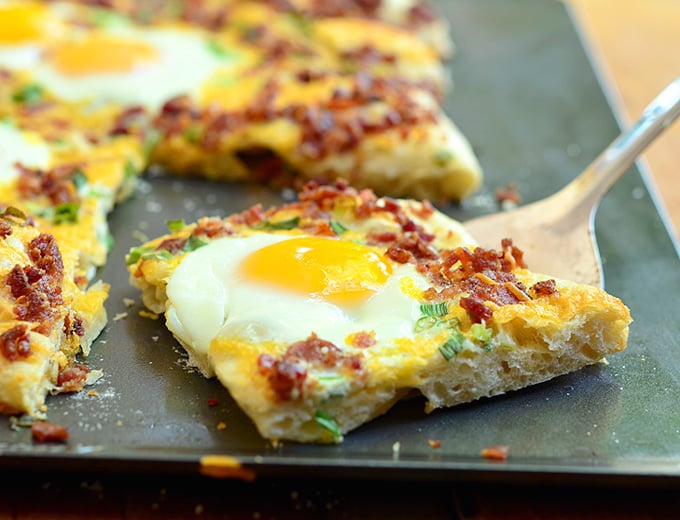 Make Breakfast Pizza with bacon, sunny side up eggs, and cheddar cheese. It's so easy to make pizza with refrigerated pizza dough!