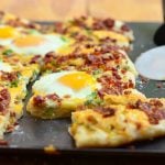 Cheesy Breakfast Pizza topped with crumbled bacon, sharp cheddar cheese, and sunny-side up eggs. Hearty and delicious, it's the best way to start your day!
