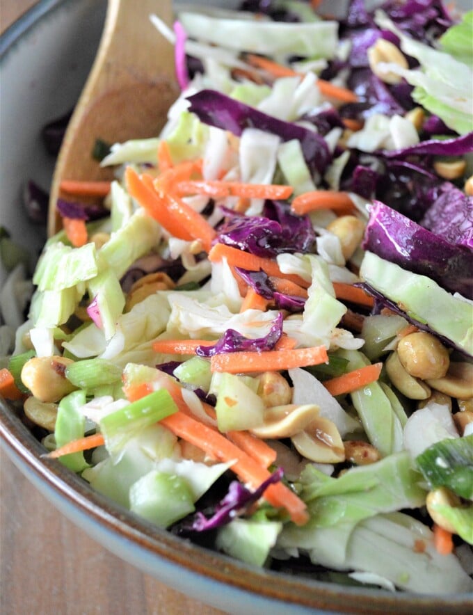 Wood Ranch BBQ and Grill copycat peanut coleslaw in bowl with a wooden spoon for serving.