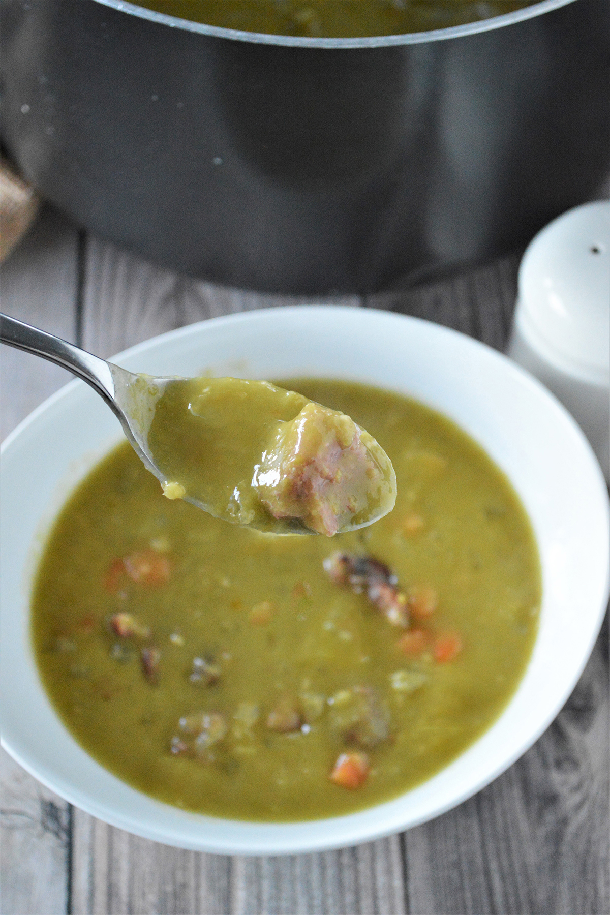 eating split pea soup with ham in a white bowl