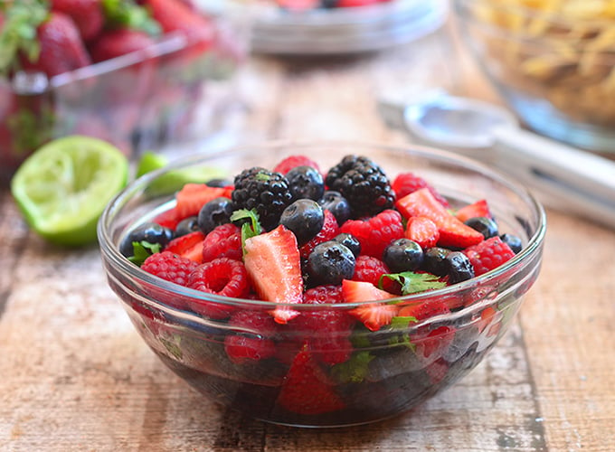berry salsa with blueberries, blackeberries, strawberries and raspberries in a clear serving bowl with a side of tortilla chips