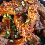 Asian Coffee Ribs garnished with green onions in a black bowl.