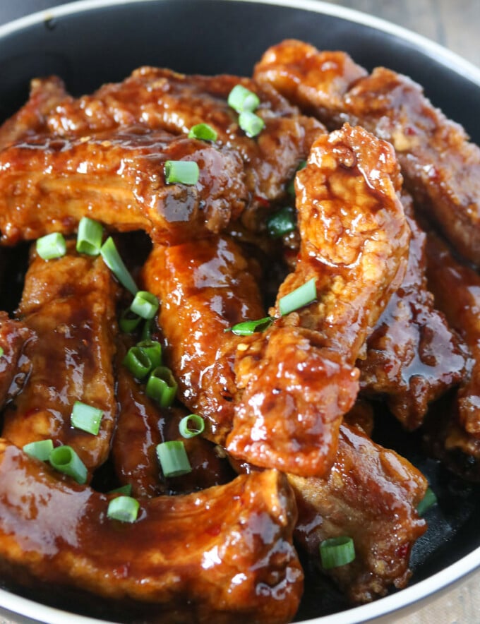 Asian Coffee Ribs garnished with green onions in a black bowl.