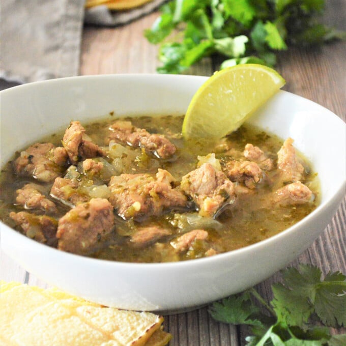 Pork Chili Verde in a white bowl with tortilas on the side