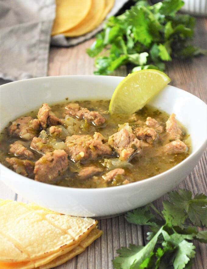 Pork Chili Verde in a white bowl with tortilas on the side