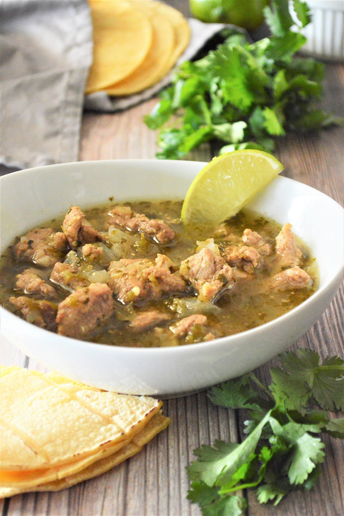 Pork Chili Verde in a white bowl with tortilas on the side