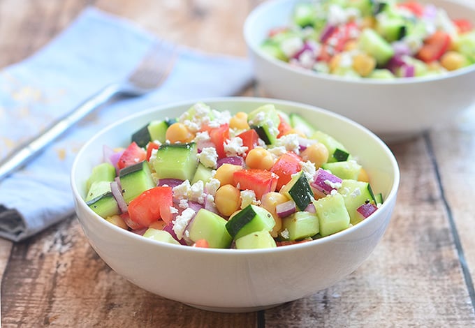 Cucumber Tomato and Feta Salad with crisp cucumbers, tomatoes, garbanzo beans, and red onions tossed in a tangy red wine vinaigrette. Chock-full of amazing texture and flavor, it's sure to be a hit with the crowd!