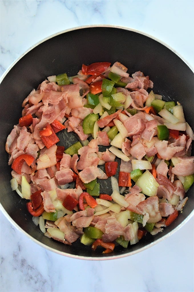 sauteed bell peppers, tomatoes, bacon in a skillet