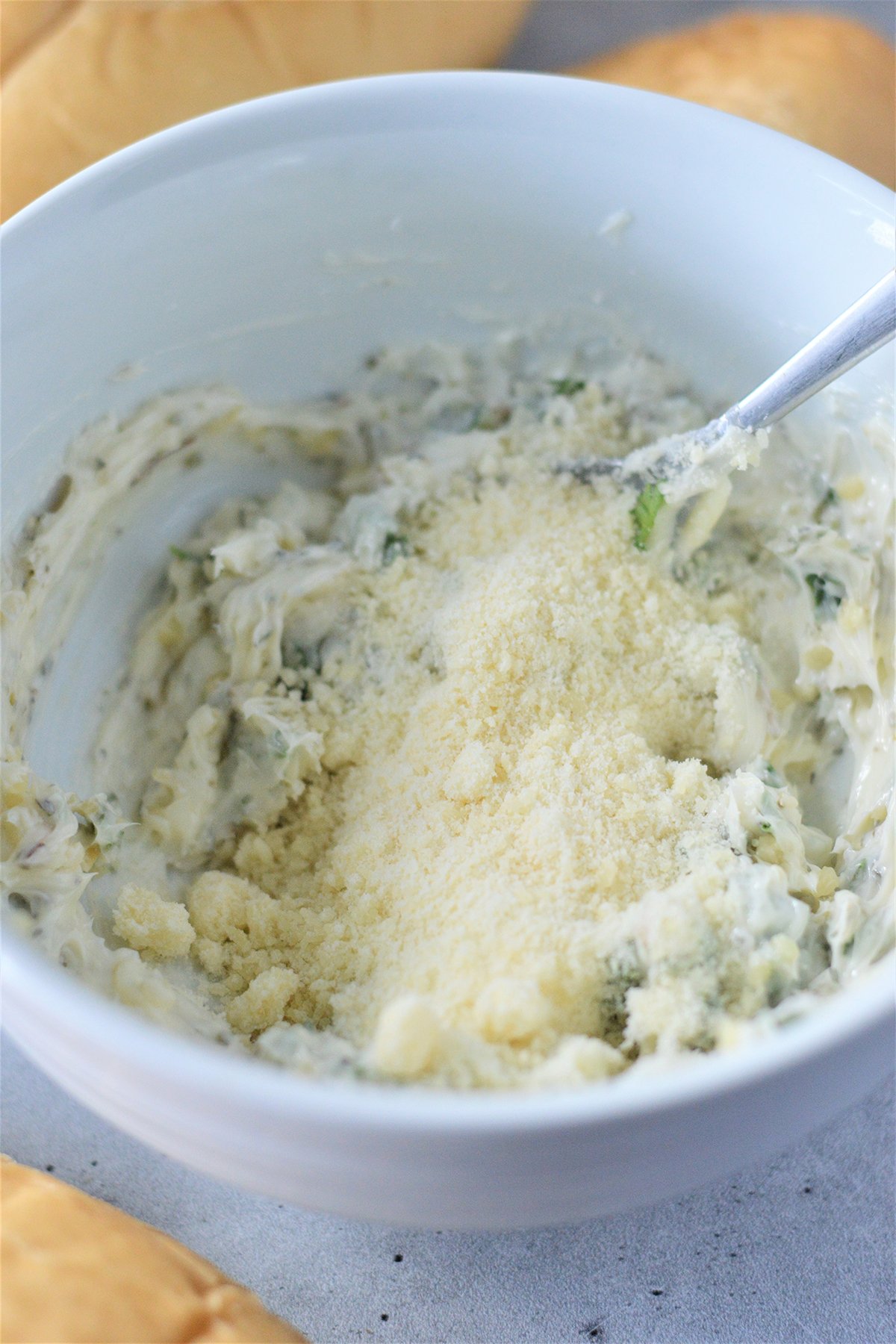 butter, parmesan cheese, herbs, minced garlic mixture in a white bowl
