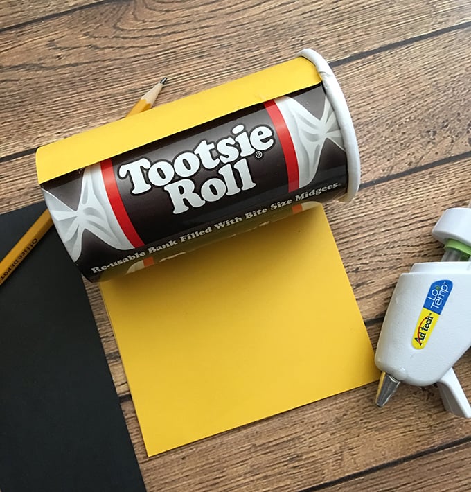 Glue the construction paper to the outside of the coin bank tube