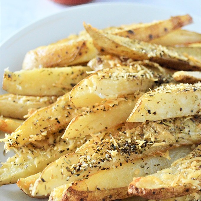 Baked Parmesan Potato Wedges are golden, crisp and loaded with delicious Parmesan and garlic flavors yet baked for a less-guilt snacking! on a plate with a side or ketchup