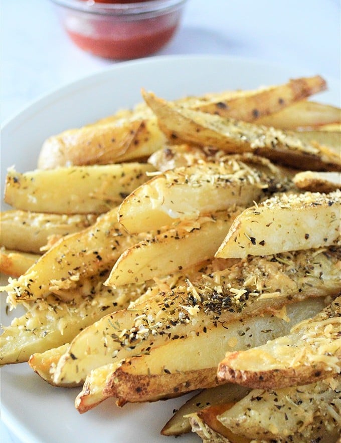 Baked Parmesan Potato Wedges are golden, crisp and loaded with delicious Parmesan and garlic flavors yet baked for a less-guilt snacking! on a plate with a side or ketchup