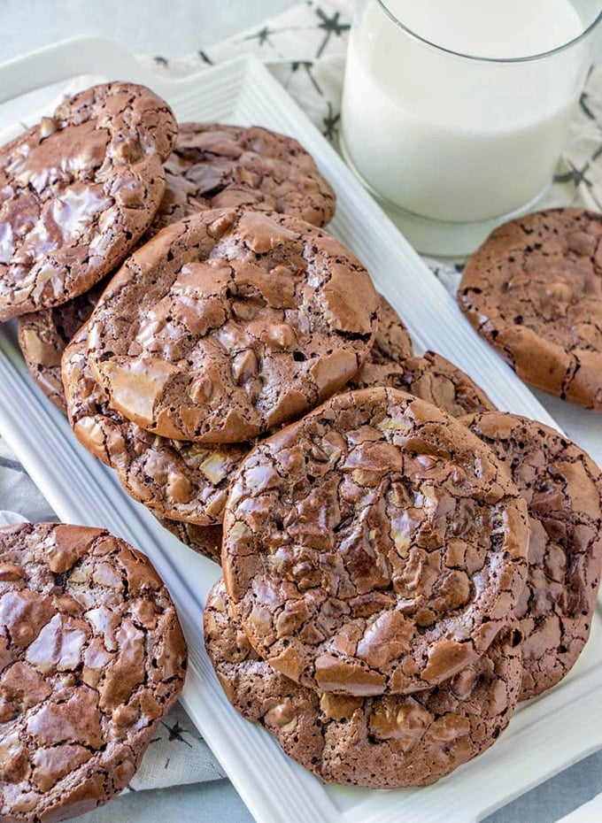 Flourless chocolate fudge cookies on a plate with a glass of milk on the side