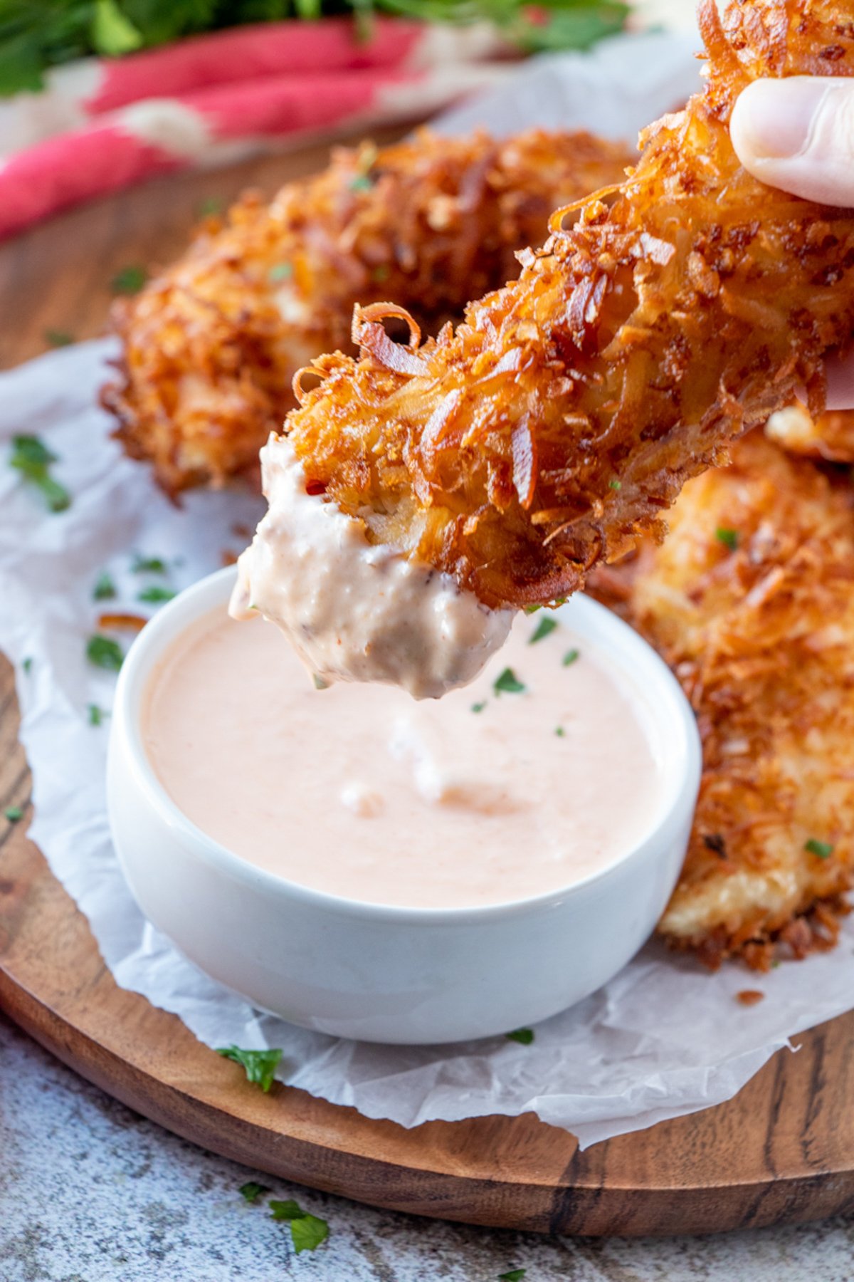 dipping coconut chicken tenders in a spicy mango sauce