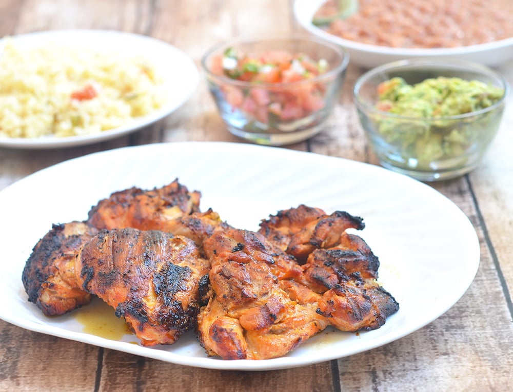 Mexican roasted chicken fresh off the grill and served with rice, beans, and condiments