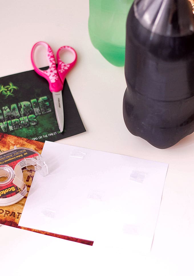 placing tape on back of Halloween soda labels to secure on soda bottles